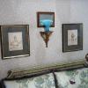 A Short Hills, NJ bedroom decorated with his & her golf prints, a 1930's French headboard and a blue Fenton glass vase on an Italian giltwood shelf.